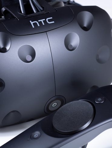 HTC Vive VR headset with controller in front of it.